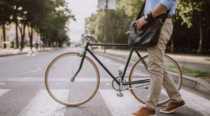 a man walking his bike across a crosswalk